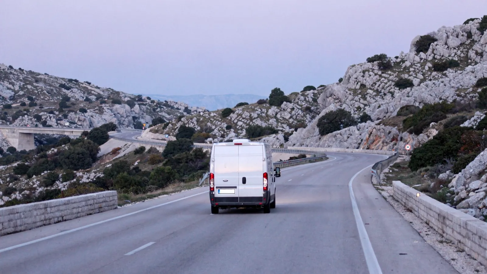 Bijeli kombi bez oznaka vozi autocestom kroz krški kraj u ranim jutarnjim satima